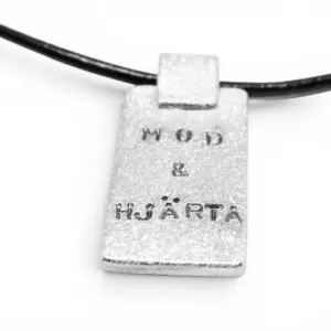 borstad silverbricka med texten Mod & Hjärta i läderrem