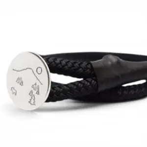 svart tamp som armband med silverbricka med mönster