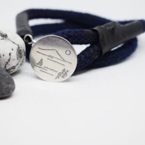 Marinblått armband med silverbricka på vit botten med stenar bredvid
