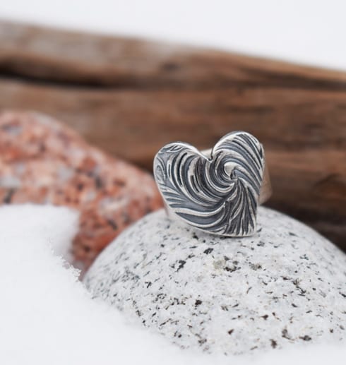 silverring med mösntrat hjärta på stenar med trä och snö utomhus