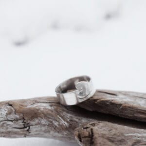 silverring med utsågat hjärta på trä utomhus