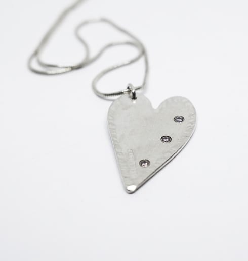 silverhjärta med stenar på vit bakgrund