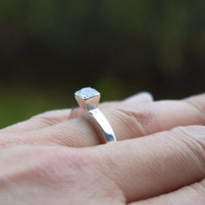 silverring med stor sten på finger utomhus