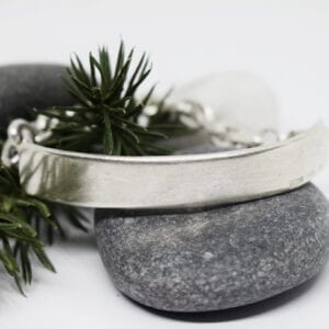 silverarmband på stenar med grankvist