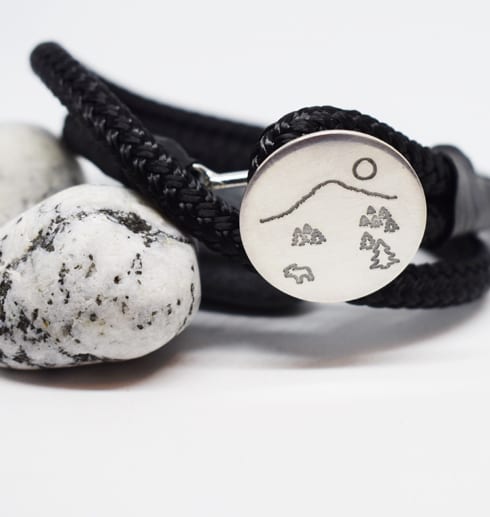 svart armband med silverplatta på stenar
