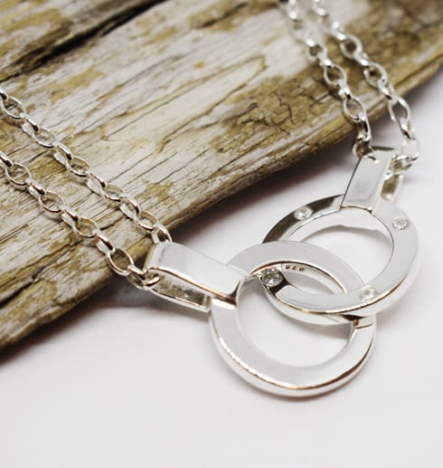 halsband med dubbla ringar i silver med träbit och vit bakgrund