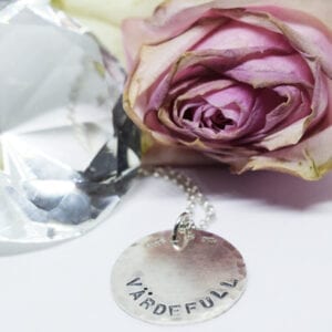 silverhalsband med texten VÄRDEFULL med ros och diamant bredvid