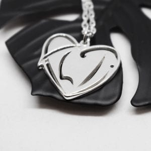 silversmycke i form av ett hjärta på svart metallblomma