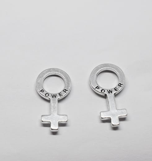 silverörhängen i form av kvinnosymbolen på vit bakgrund