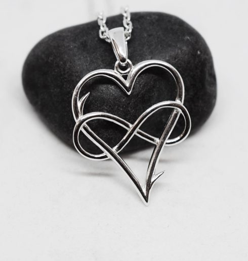 silverhjärta med evighetssymbol på svart sten
