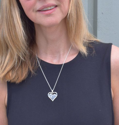 silversmycke i form av ett hjärta på kvinna med svart klänning utomhus