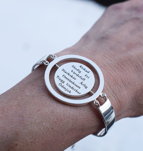 silverarmband med text på kvinnas arm utomhus