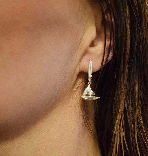 silverörhängen i form av segelbåt på kvinnas öra