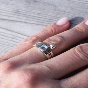 silverring på kvinnas finger med hjärtan