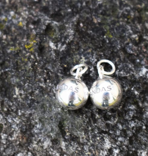 silverörhängen i form av bollar på sten