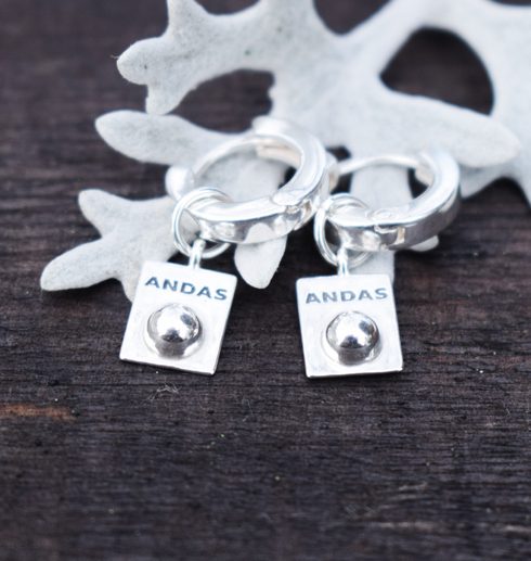 silverörhängen mot silverfärgat blad