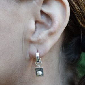 silverörhänge med texten ANDAS i kvinnas öra