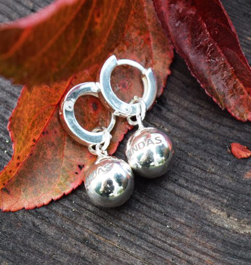 silverörhängen i form av bollar på orange löv
