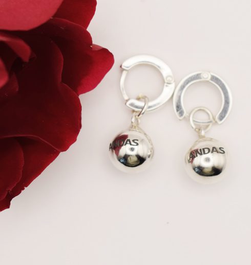 silverörhängen i form av ANDAS-bollar med röd ros bredvid