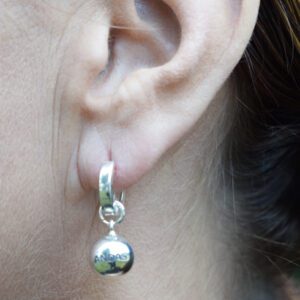 silverörhängen i form av bollar på kvinnas öra