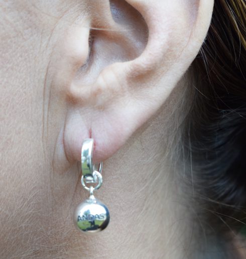 silverörhängen i form av bollar på kvinnas öra