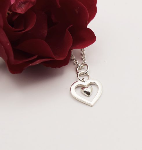 silverhalsband i form av ett hjärta med en röd ros bredvid